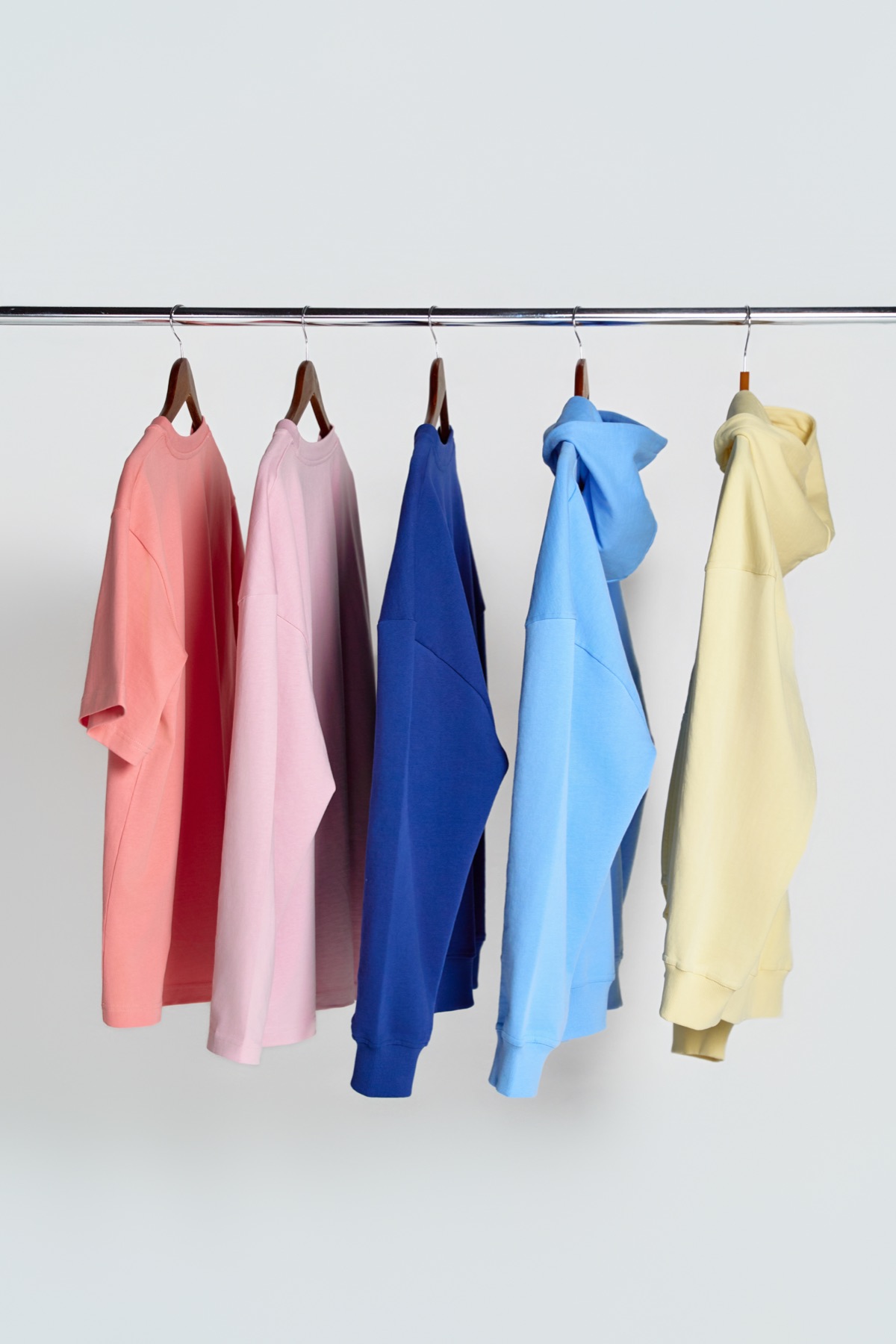 Five Orbit garments in pastel colorways hanging on a rail